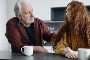 A touching moment between a grandfather and granddaughter sharing emotions indoors over coffee.